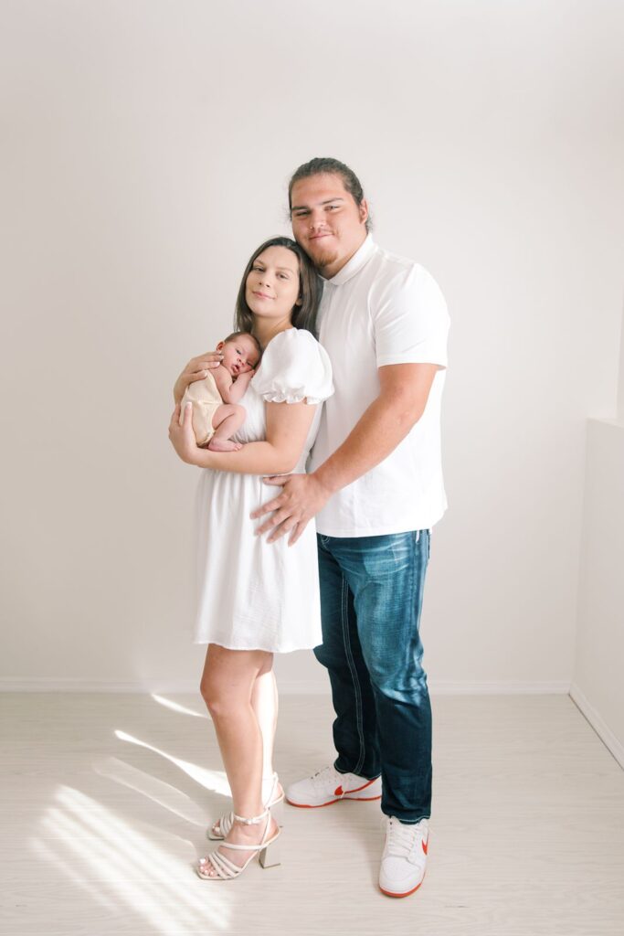 family with newborn smiling in a photography studio